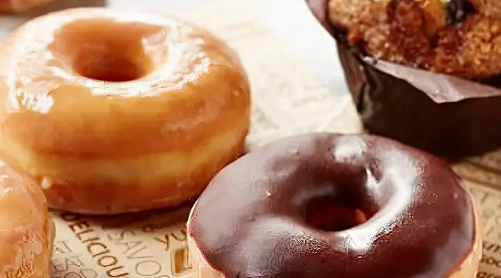 Plain glazed donut, a chocolate glazed donut, and blueberry muffin.