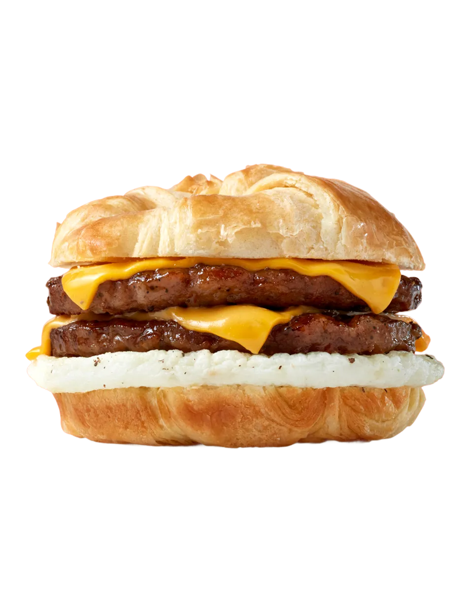 breakfast croissant sandwich with two pieces of sausage, two slices of cheese, and a fried egg